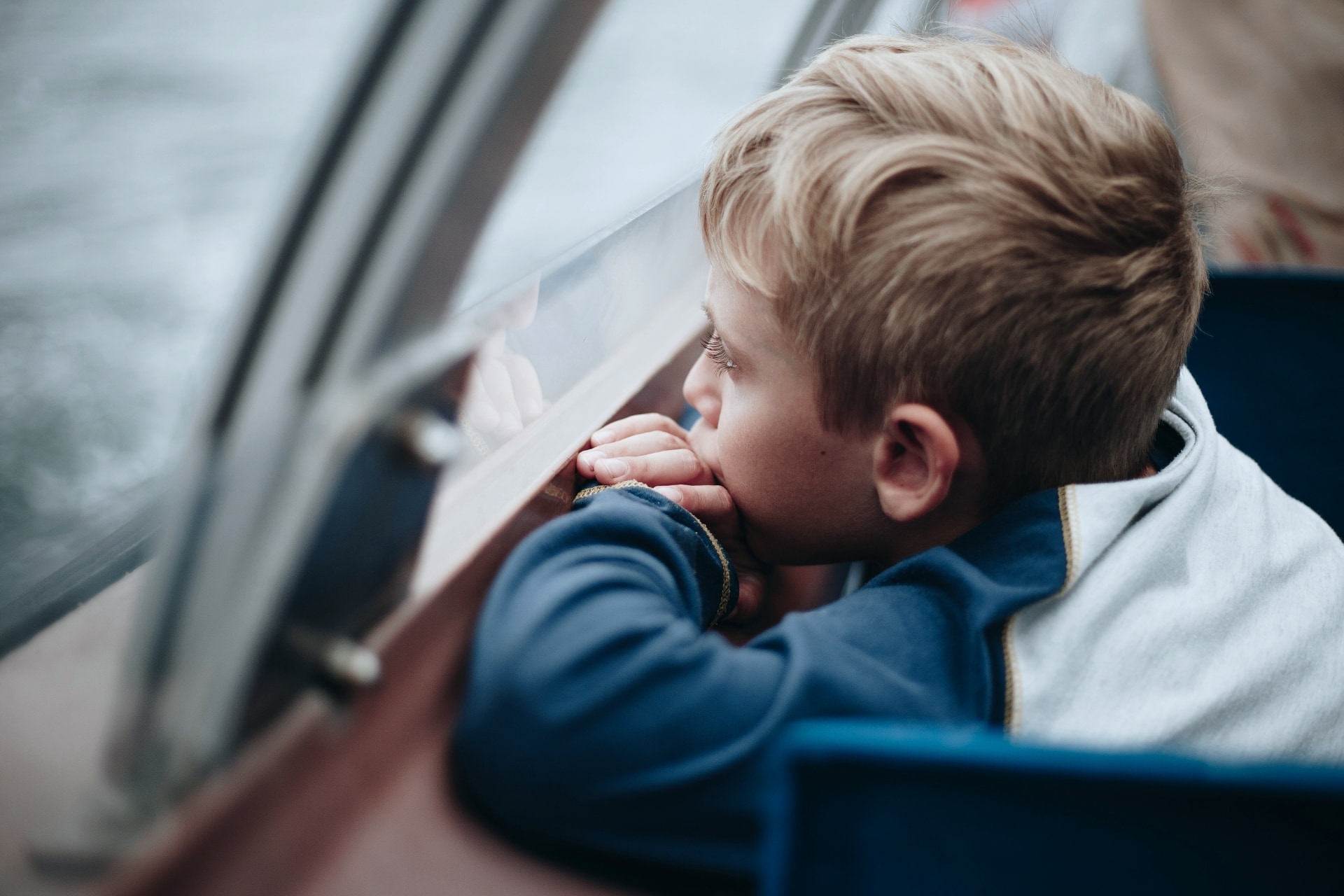 Young child leaning on a car window and looking outside
