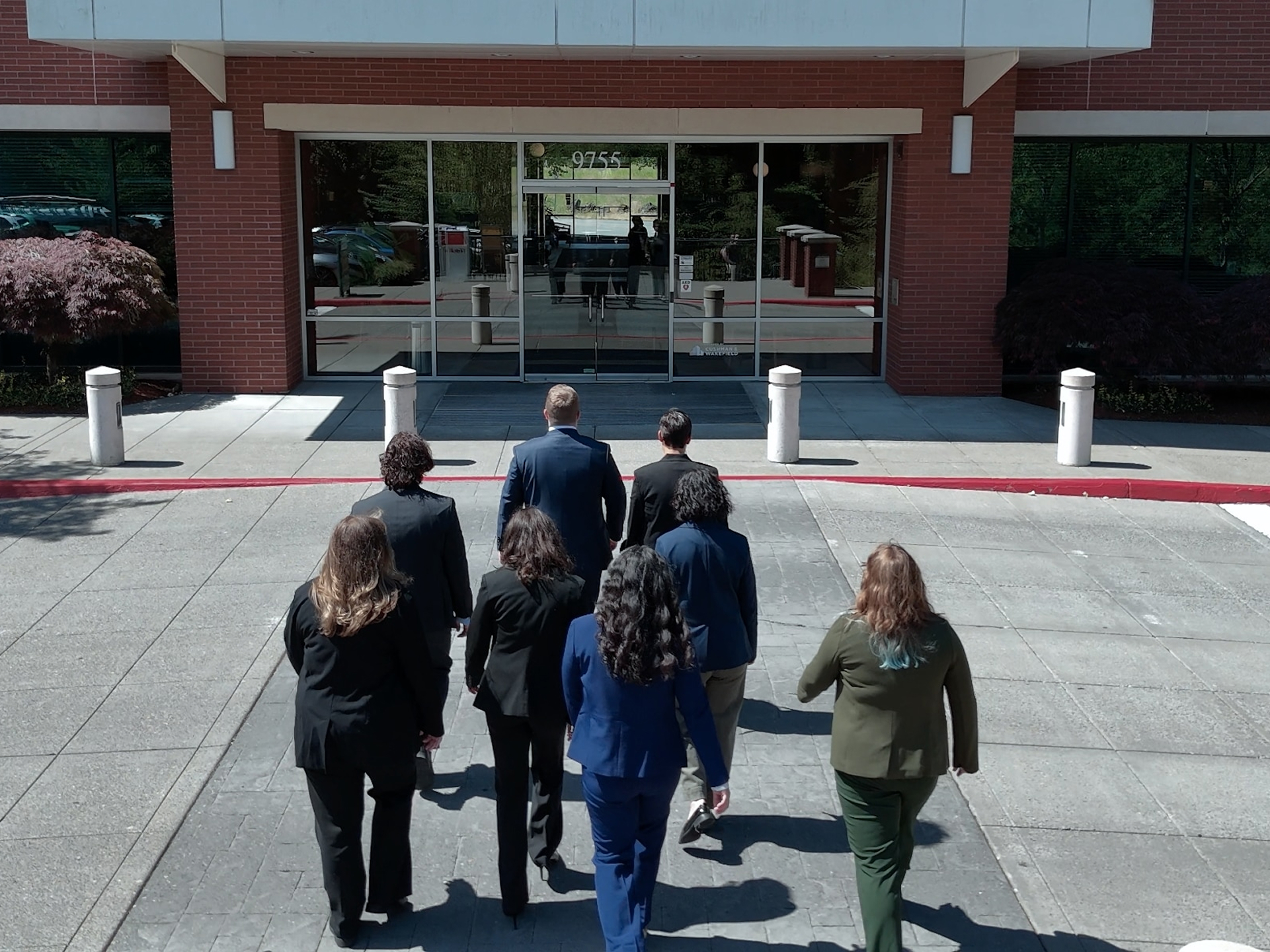 Group of professionals in business attire walking together toward the entrance of an office building